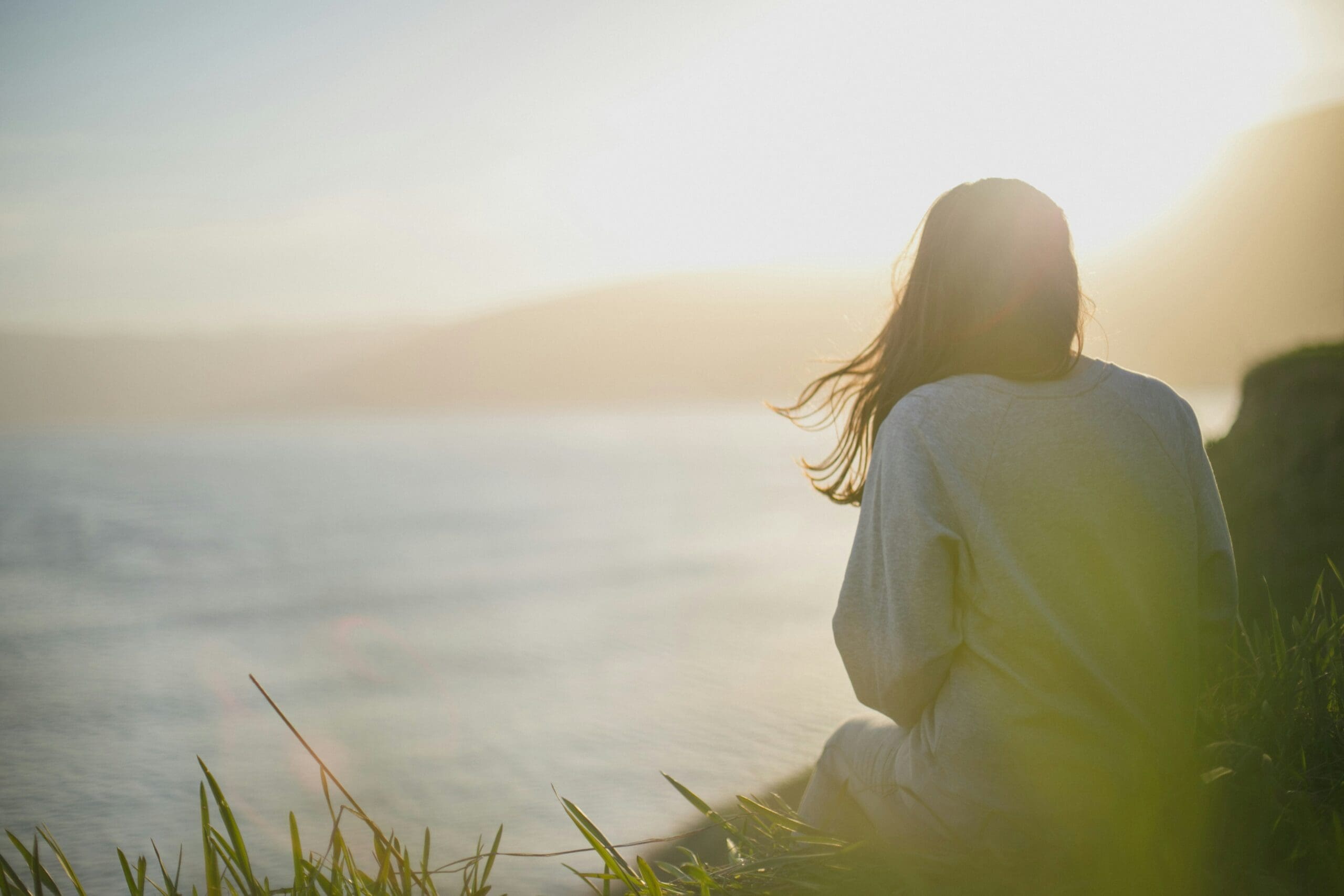 a woman overlooking the ocean thinking about if she can heal trauma without reliving it