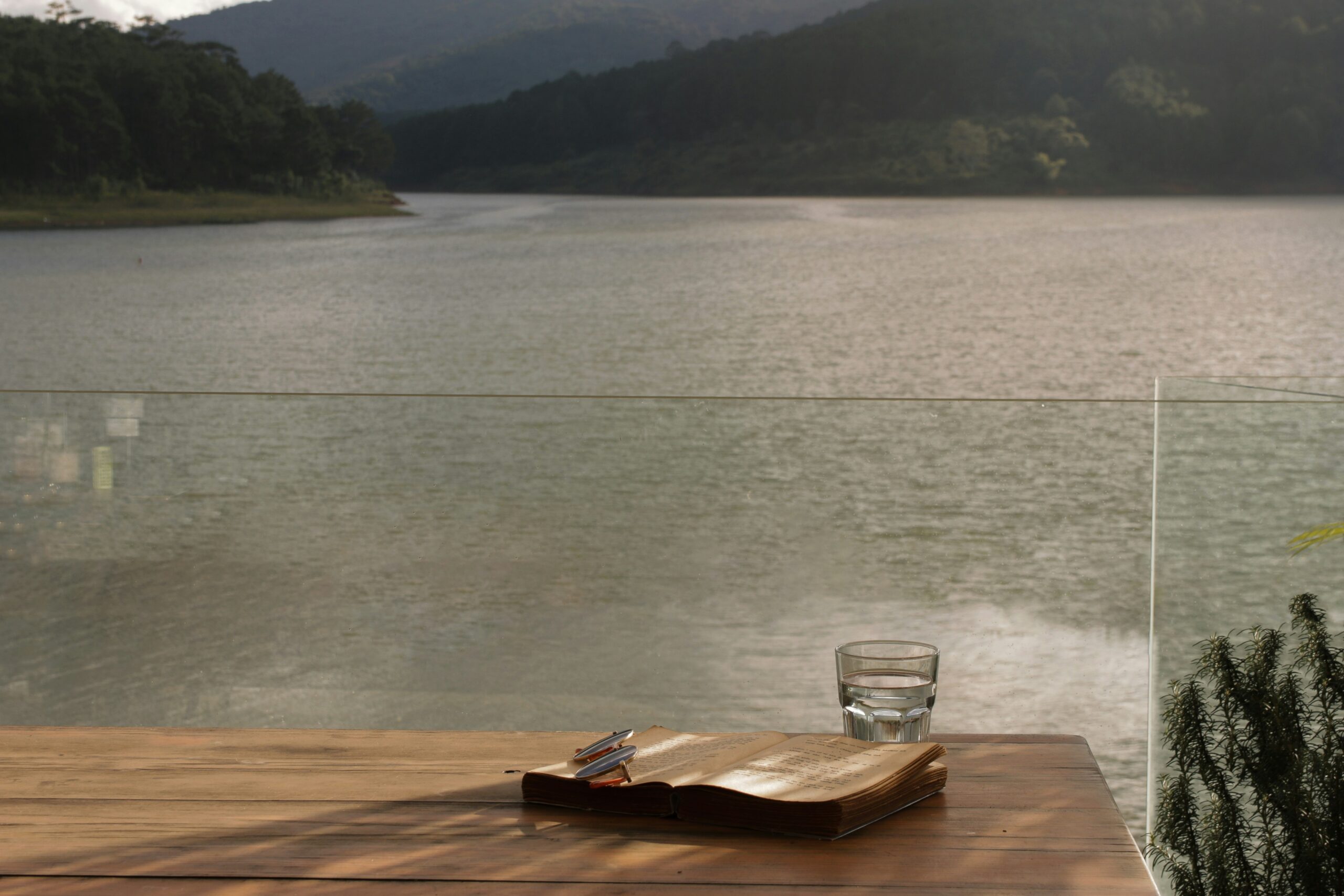 glass of water on a table overlooking a lake showing that grounding is about being present
