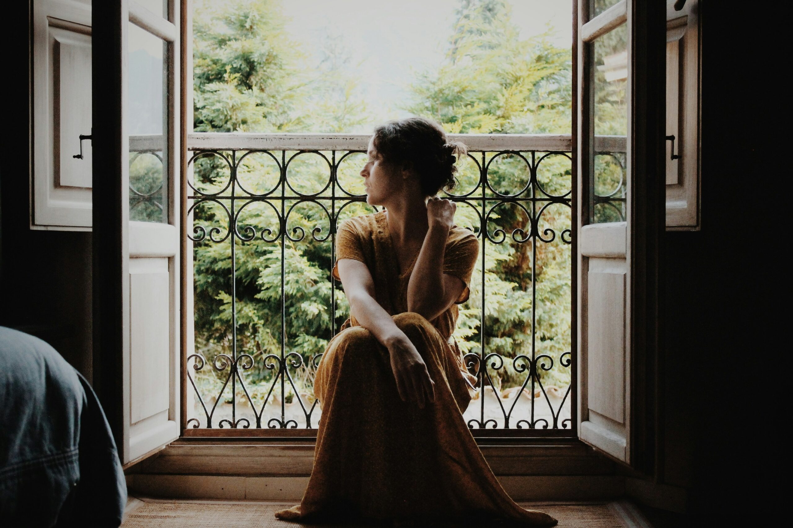 a woman looking out the window showing that calm can look uncomfortable when you are in survival mode