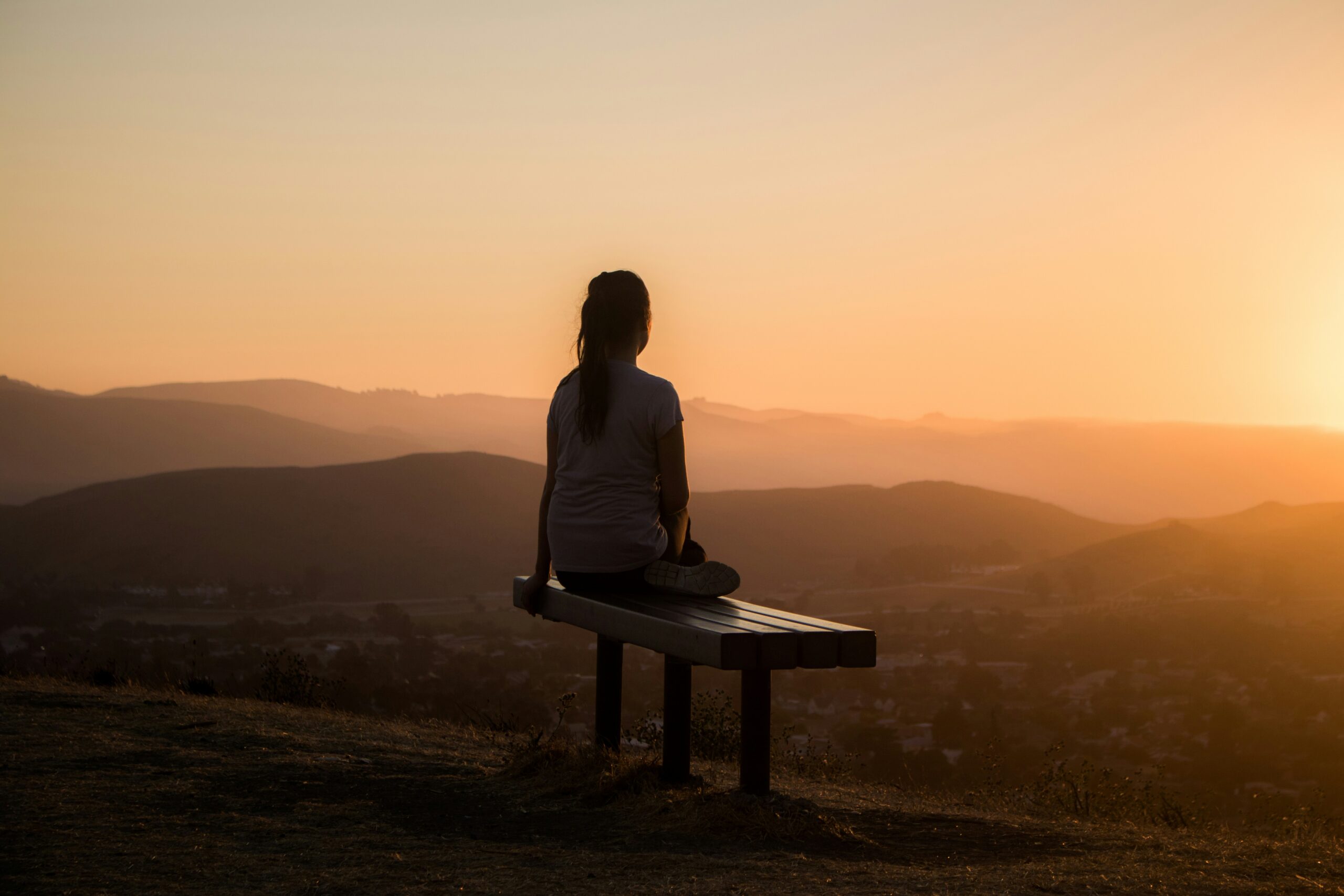 a woman overlooking the sunset reminding us that healing begins when we understand the root cause